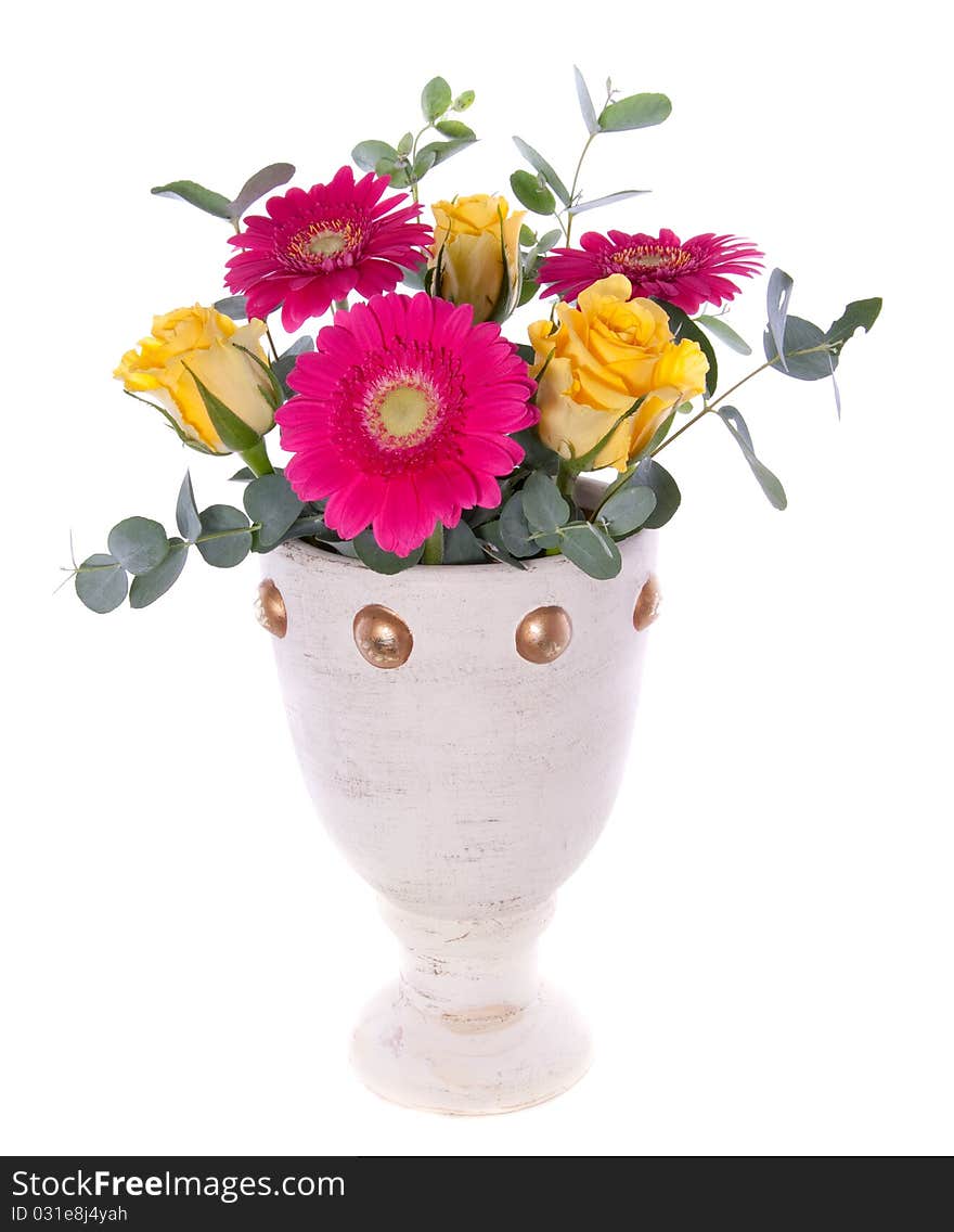 Yellow roses and pink Gerber with Eucalypthus in a ceramix white vase isolated over white background