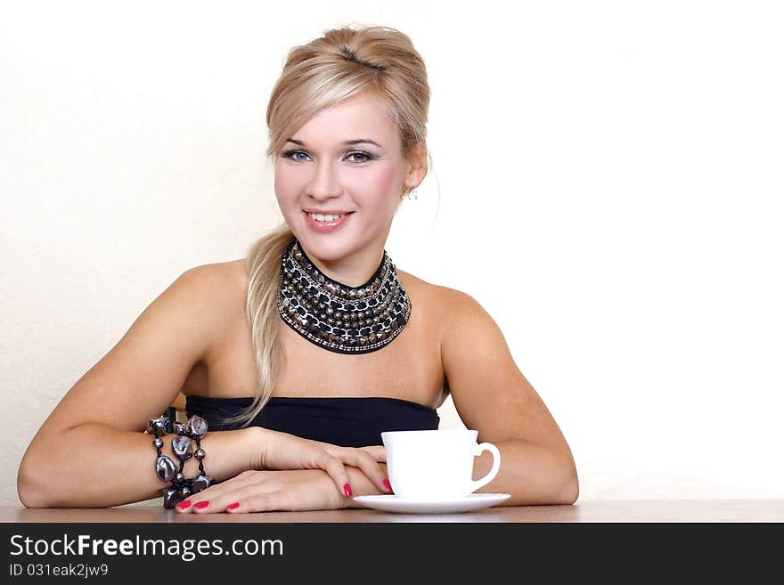 Woman with cup of hot drink against yellow wall at home