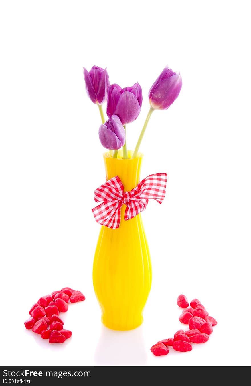 Purple tulips in a yellow little vase decorated with stones isolated over white. Purple tulips in a yellow little vase decorated with stones isolated over white