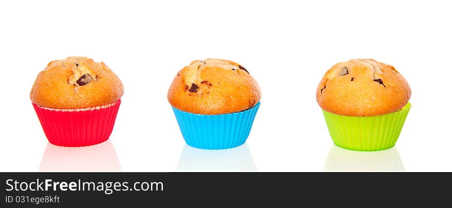 Three muffins with chocolate abreast in colorful cupcake-molds  isolated over white