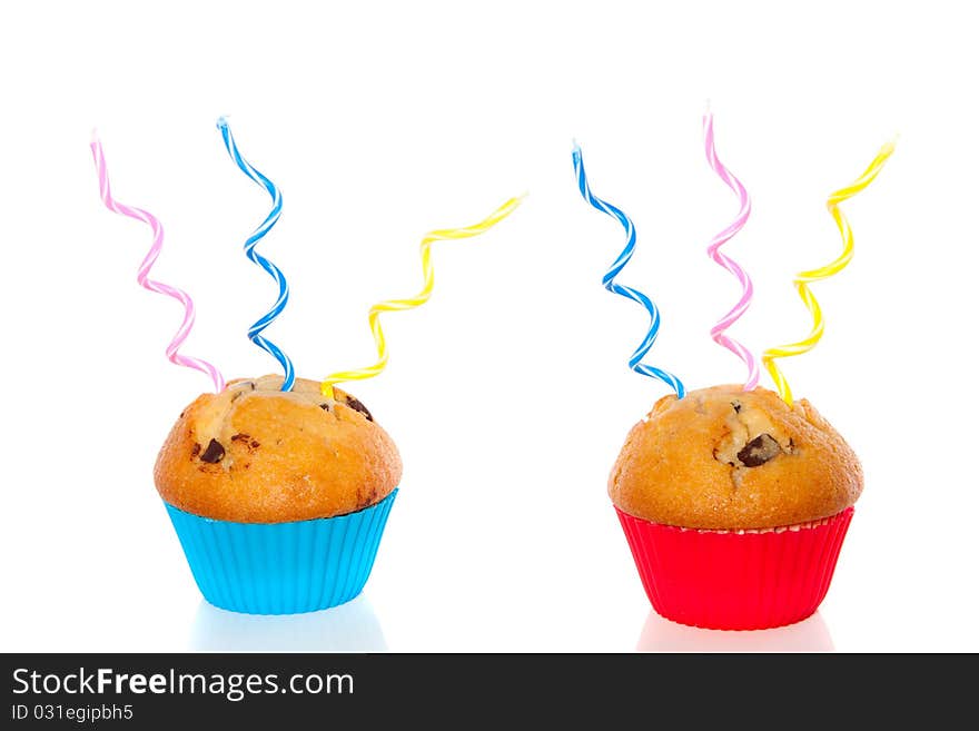 Two colorful muffins decorated with festive candles isolated over white