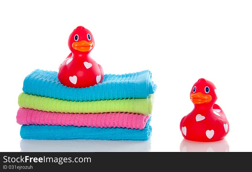 Lovely red ducks on a stack of colorful towels isolated over white. Lovely red ducks on a stack of colorful towels isolated over white