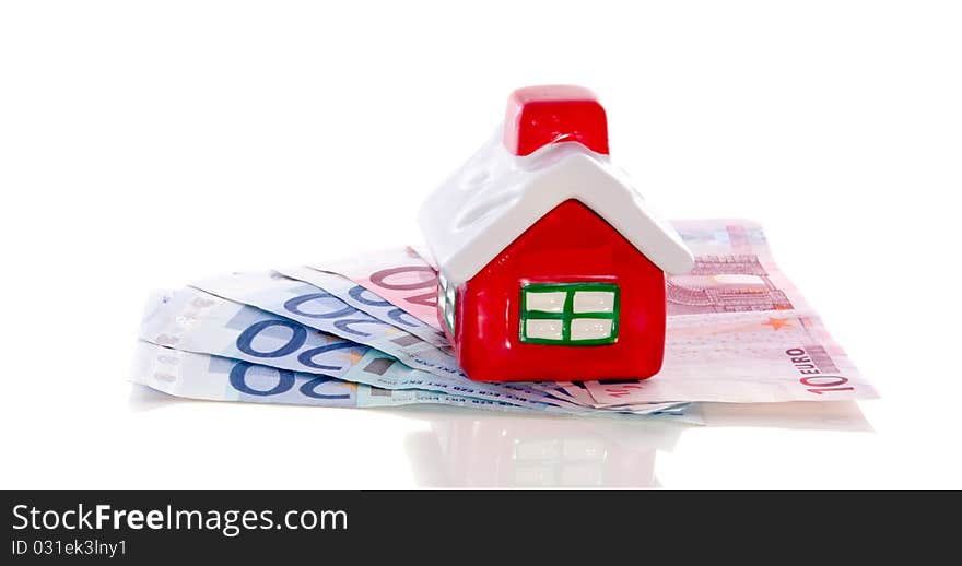 Colorful little house on top of bank notes isolated over white. Colorful little house on top of bank notes isolated over white