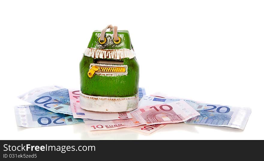 A green money-box on top of euro banknotes isolated over white. A green money-box on top of euro banknotes isolated over white