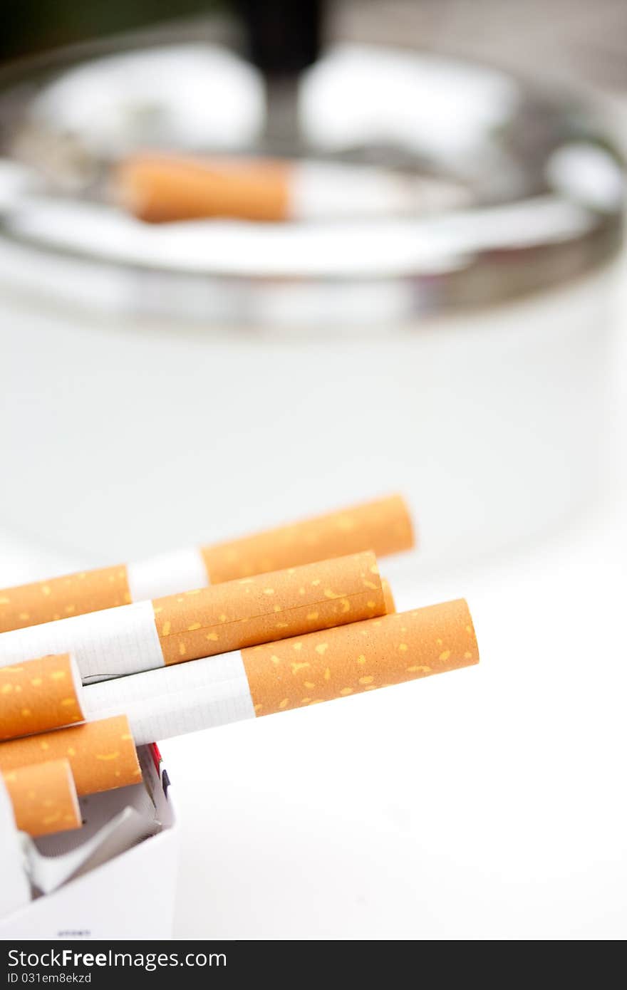 Addictive sigarettes in front of a smoking sigartette in an ash-tray isolated over white