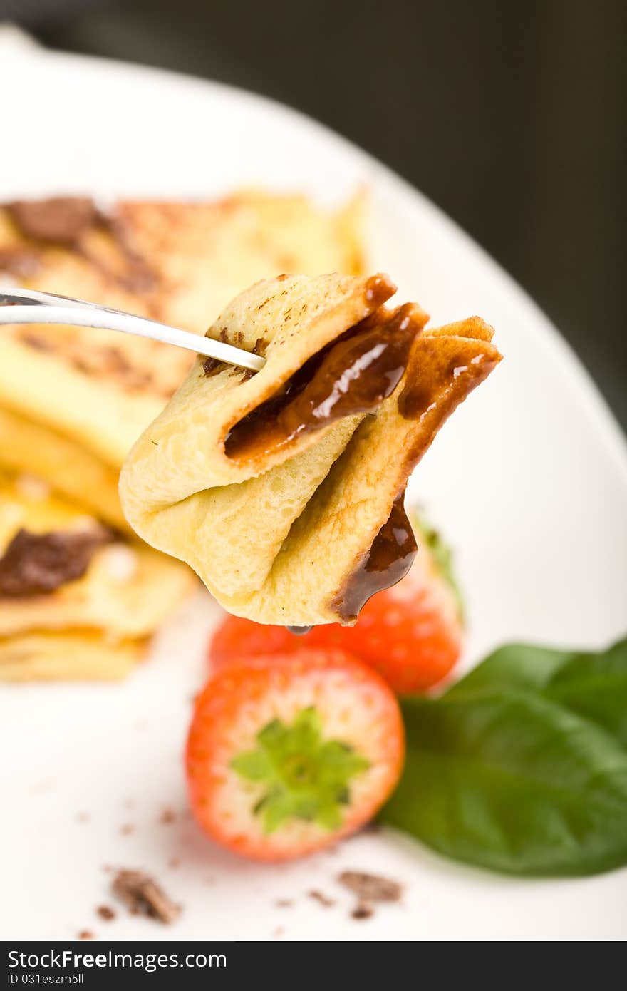 Photo of crepes with choccolate and strawberries on a white plate