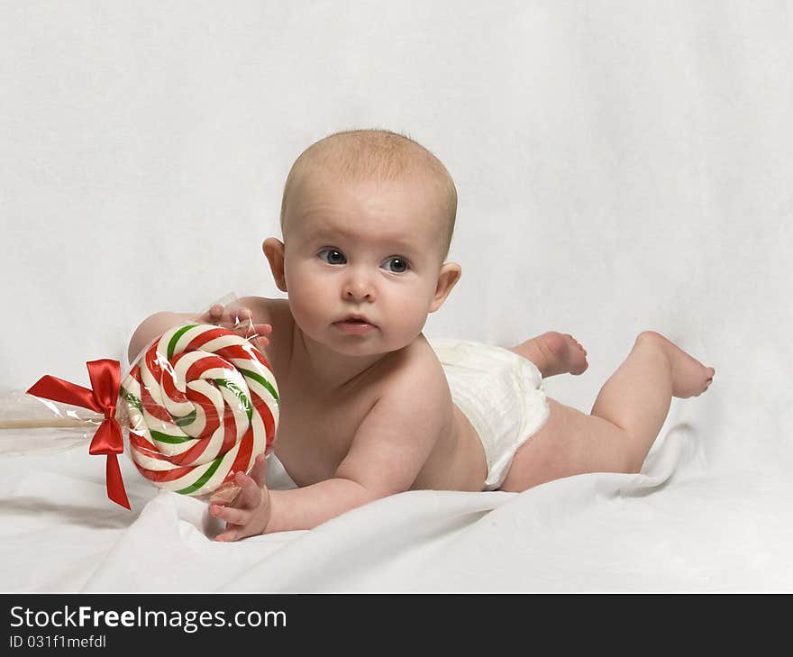 Baby on Tummy, playing with a Candy Cane Lollipop. Baby on Tummy, playing with a Candy Cane Lollipop