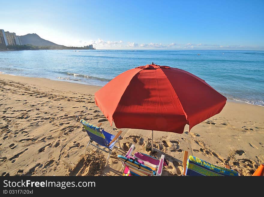 Red umbrella with chairs at the beach with Diamond Head in the background. Red umbrella with chairs at the beach with Diamond Head in the background