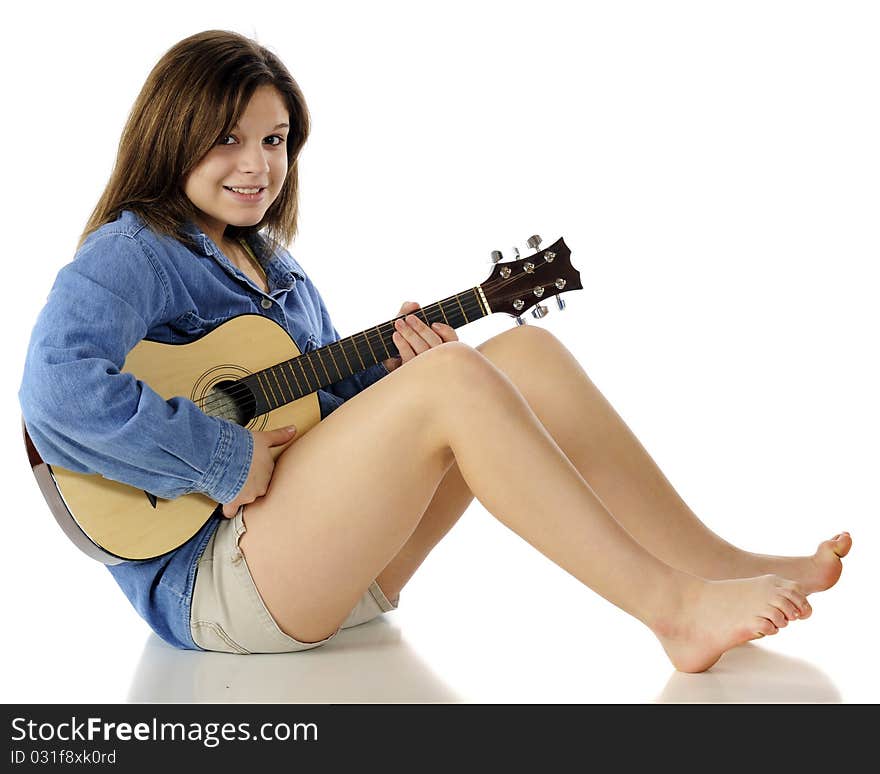 A happy, beautiful young teen sitting barefoot on the floor ready to practice her guitar. Isolated on white. A happy, beautiful young teen sitting barefoot on the floor ready to practice her guitar. Isolated on white.