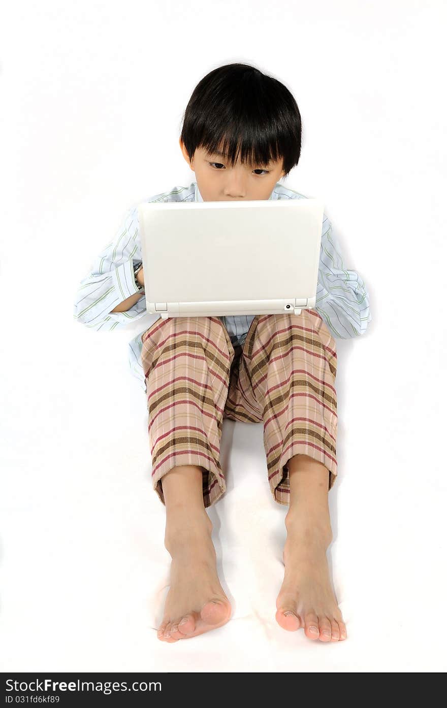 A boy is concentrated on typing his white laptop.