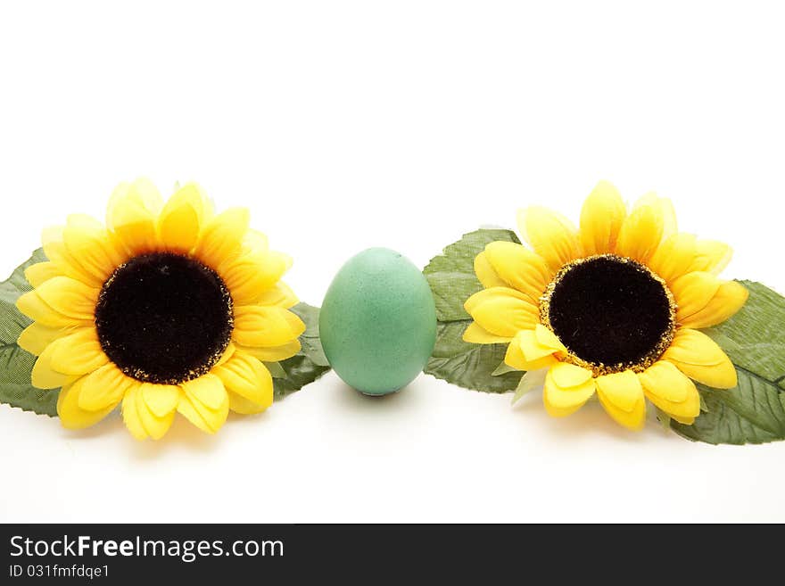 Green Easter egg between sunflowers