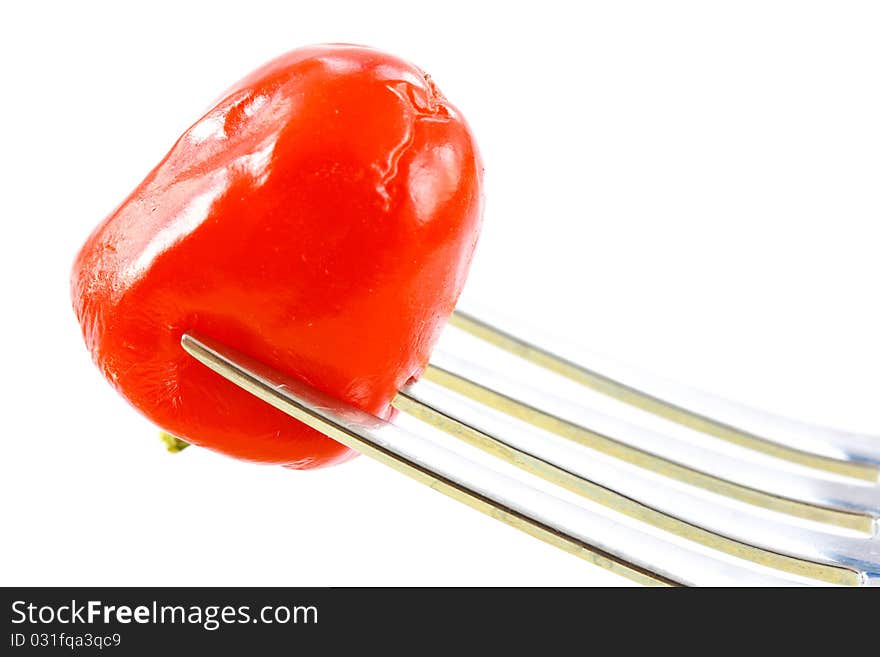 Red pepper on a fork on a white background