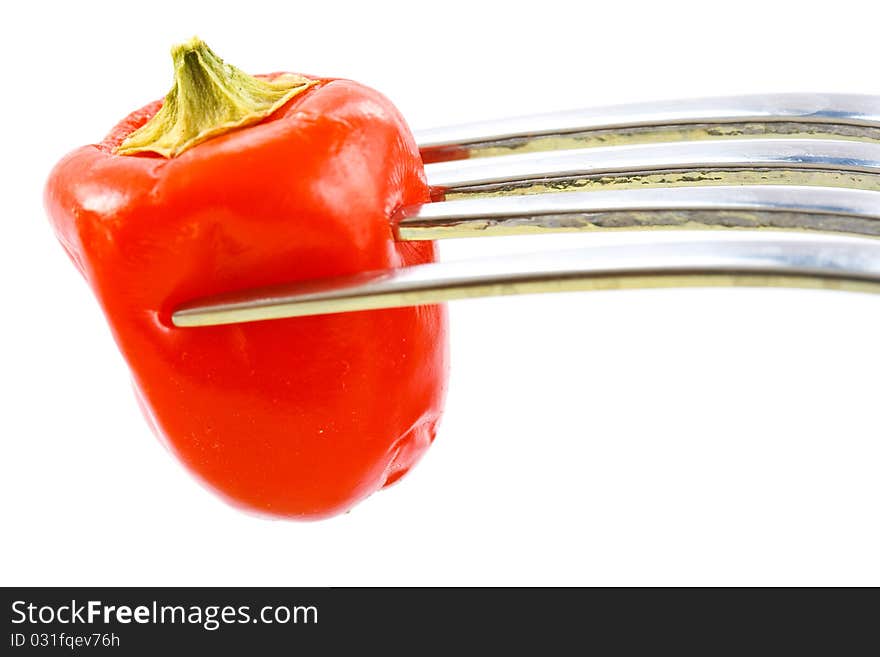 Red pepper on a fork on a white background