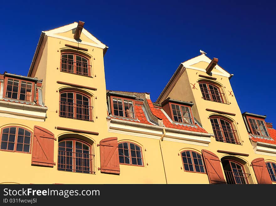 Traditional mustard colour office warehouse against a bright blue sky. Traditional mustard colour office warehouse against a bright blue sky