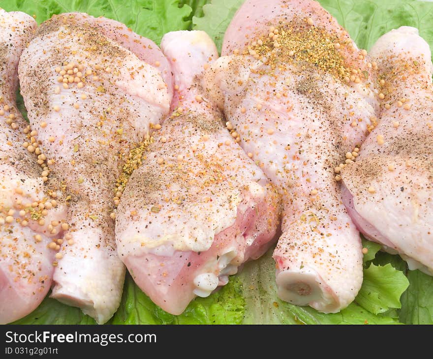 Crude chicken shins on green leaves of salad. Crude chicken shins on green leaves of salad