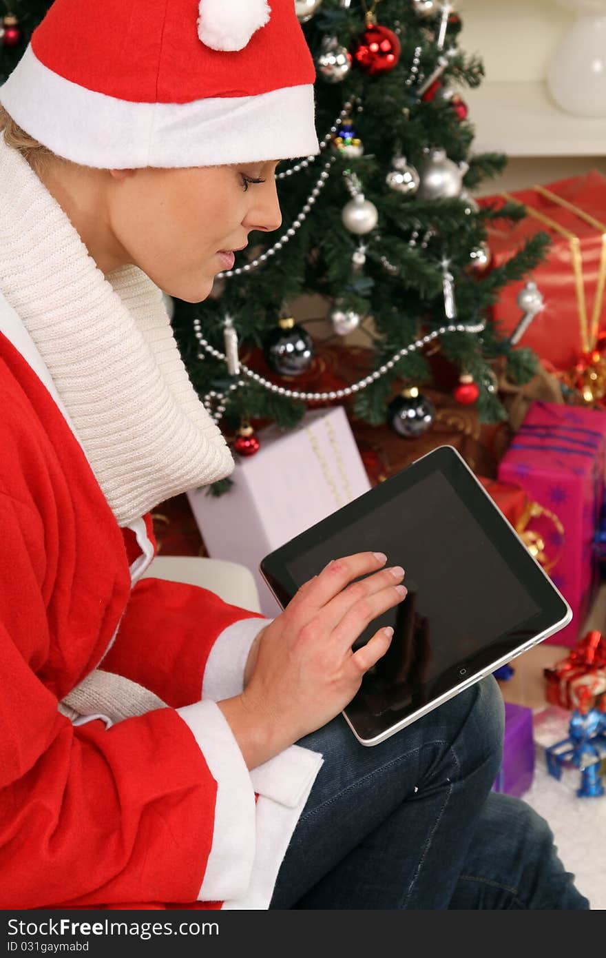 blond nikolaus sitting in front of a christmas tree with a technical present. blond nikolaus sitting in front of a christmas tree with a technical present