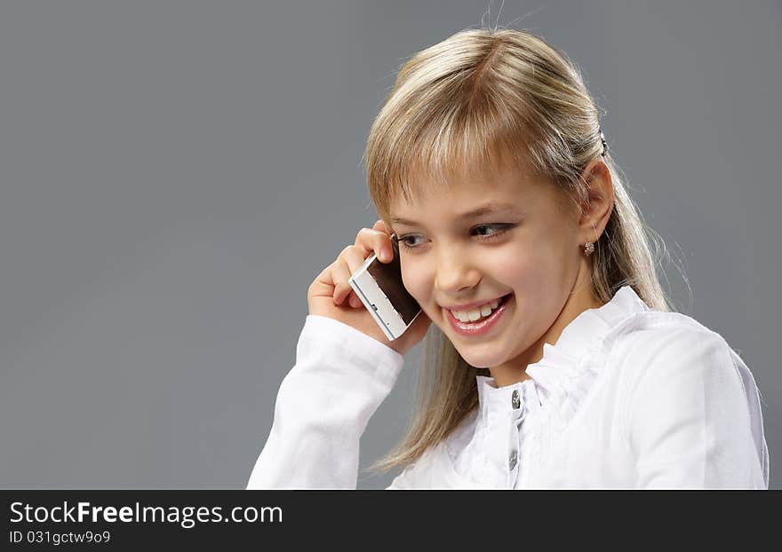 Portrait of a beautiful little girl with blond hair, talking on a mobile phone. Portrait of a beautiful little girl with blond hair, talking on a mobile phone