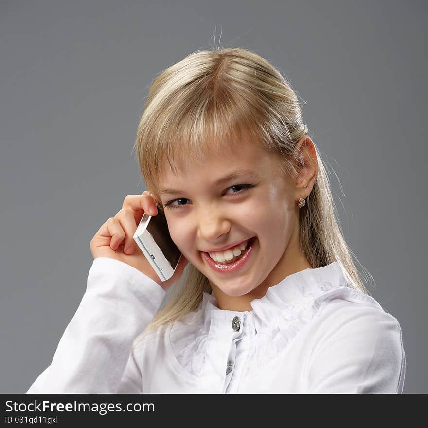 Portrait of a beautiful little girl with blond hair, talking on a mobile phone. Portrait of a beautiful little girl with blond hair, talking on a mobile phone