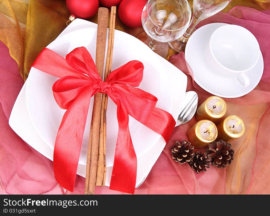 Christmas tableware, decorated with cinnamon sticks, ribbon, christmas balls, candles and cones in close up