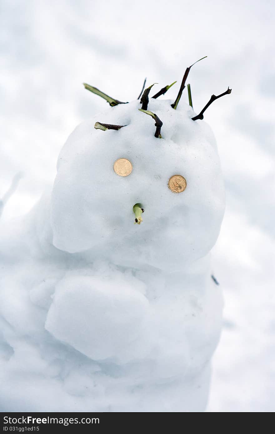 Snowman on a background of snow with coins place the eye