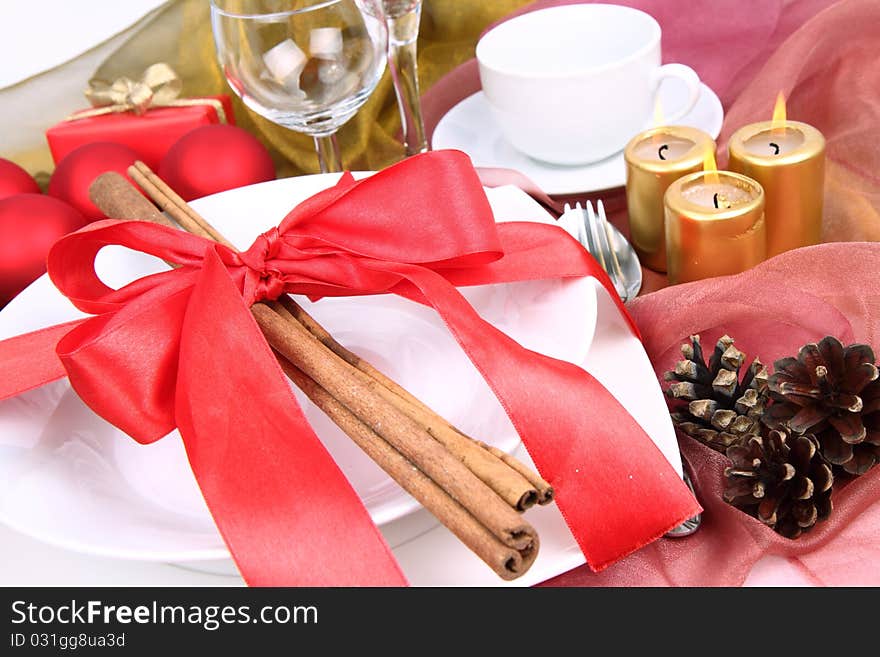 Christmas tableware, decorated with cinnamon sticks, ribbon, christmas balls, candles and cones in close up