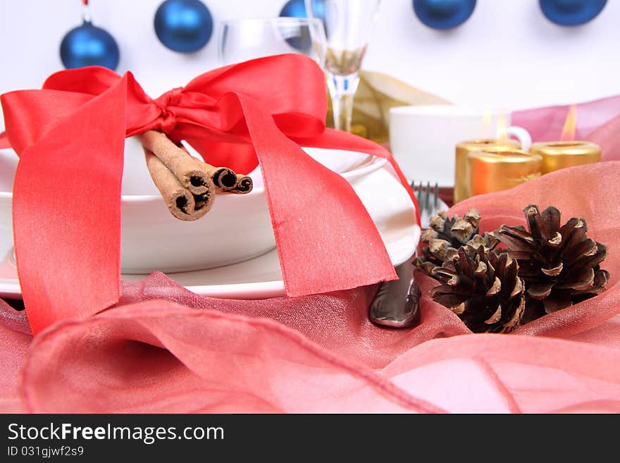 Christmas tableware, decorated with cinnamon sticks, ribbon, christmas balls, candles and cones in close up