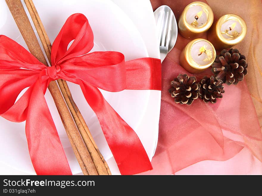 Christmas tableware, decorated with cinnamon sticks, ribbon, burning candles and cones