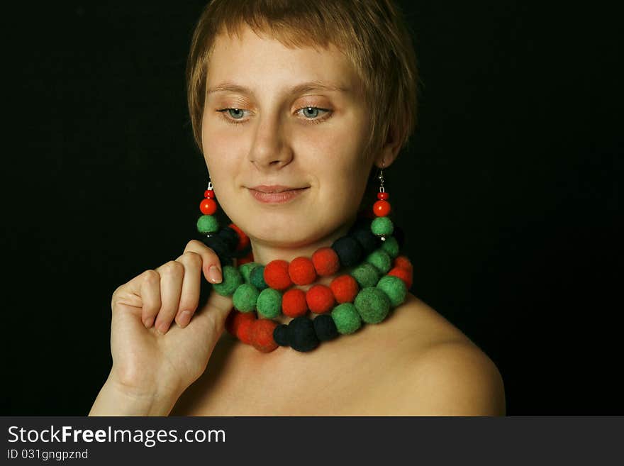 Young woman with bare shoulders in her wearing a necklace and earrings made of wool. Ethnos. Young woman with bare shoulders in her wearing a necklace and earrings made of wool. Ethnos