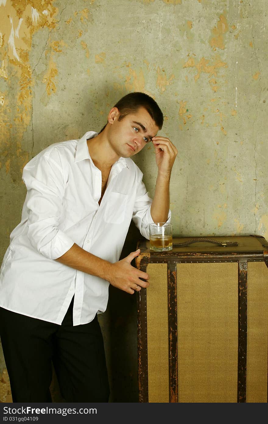 Handsome young man in the old room is based on the old suitcase next to his glass of whiskey. Handsome young man in the old room is based on the old suitcase next to his glass of whiskey