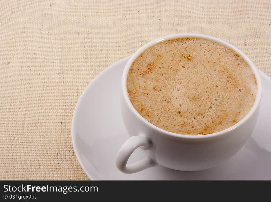 Cappuccino in a white ceramic cup with a saucer.