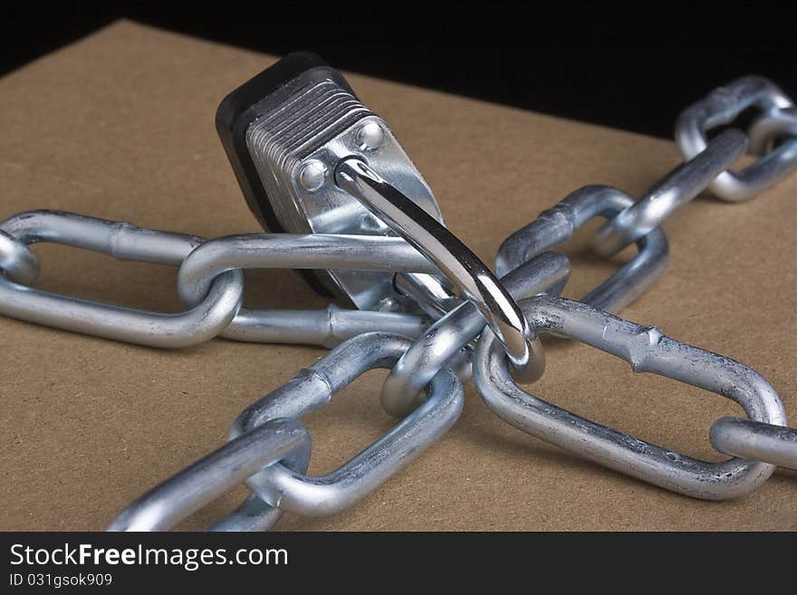 Metal lock and chain on a brown background.