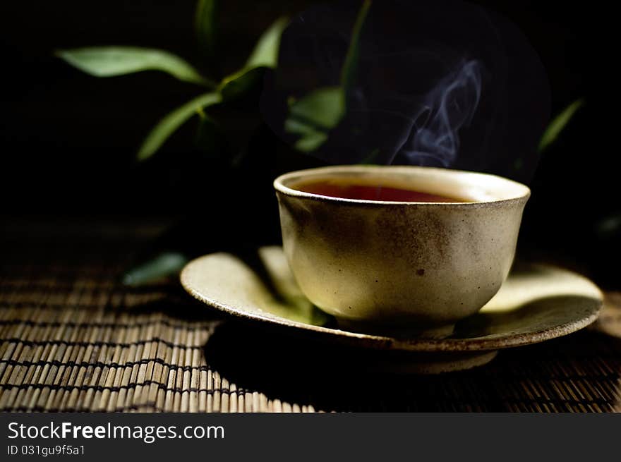 Cup of tea and twig with dark background