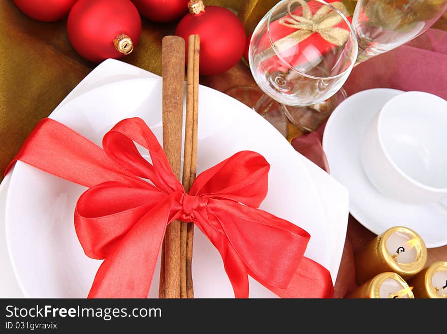 Christmas or New Year's setting, plate decorated with cinnamon sticks and ribbon with christmas balls, candles and cones in close up