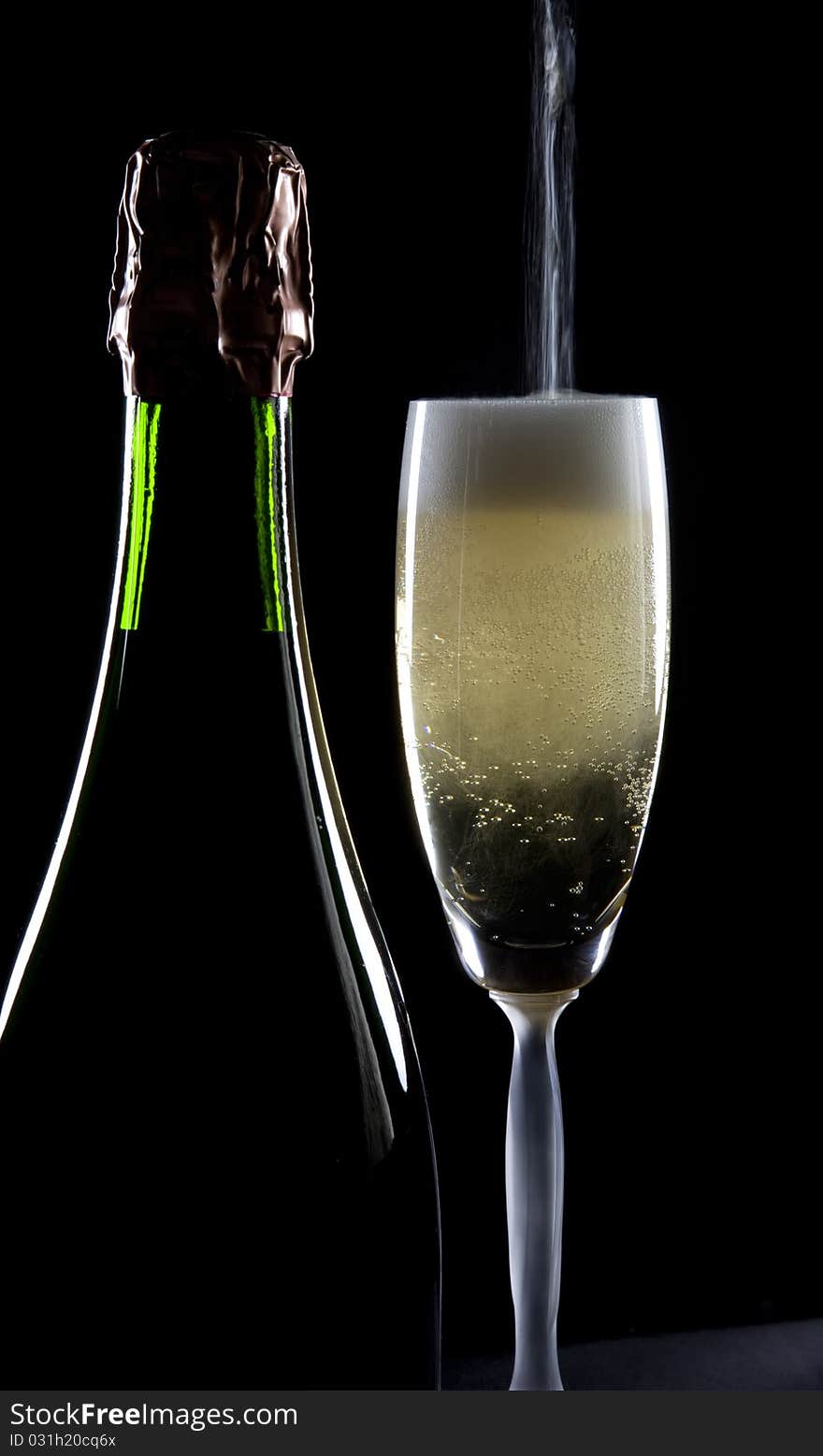 A stream of champagne fills a glass, standing by a full bottle, with bubbles. A stream of champagne fills a glass, standing by a full bottle, with bubbles.