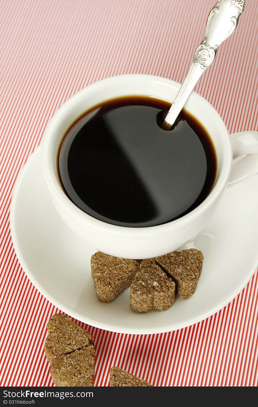 Closeup of a white cup of coffee next to lay pieces of sugar. Closeup of a white cup of coffee next to lay pieces of sugar