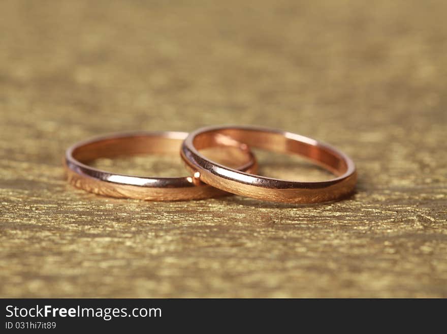 Two wedding rings on golden background