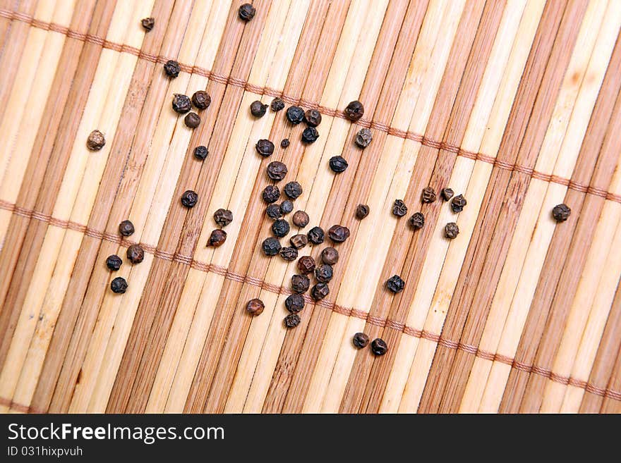 Black pepper on wooden background