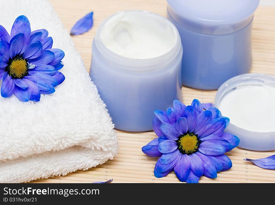 Spa essentials, cream and towel with blue flowers