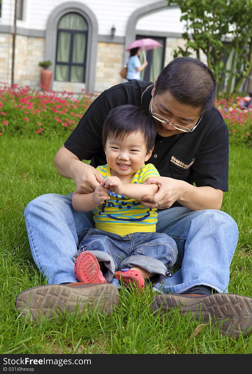 Happy baby is playing with his father on lawn