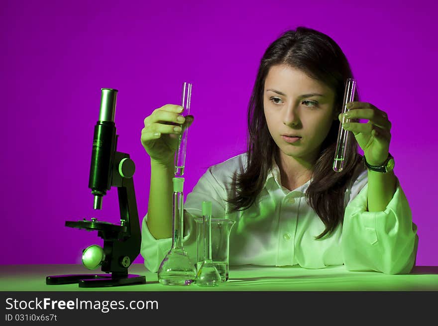 Young school girl playing with tubes and a microscope. Young school girl playing with tubes and a microscope