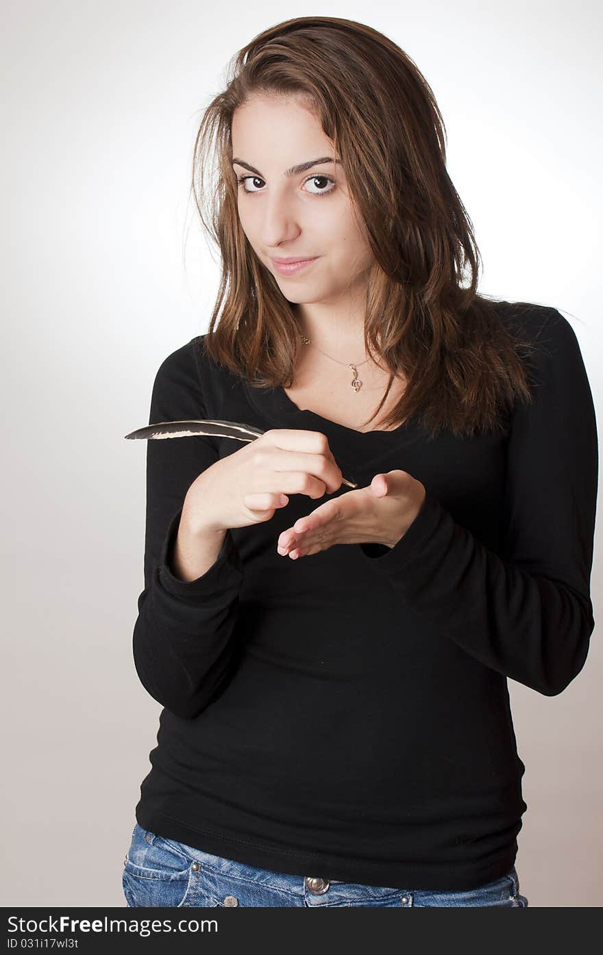 Young girl holding a feather and writing in her palm. Young girl holding a feather and writing in her palm