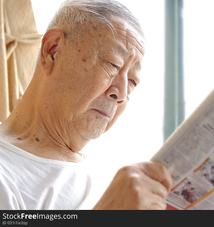 A senior man is reading newspaper