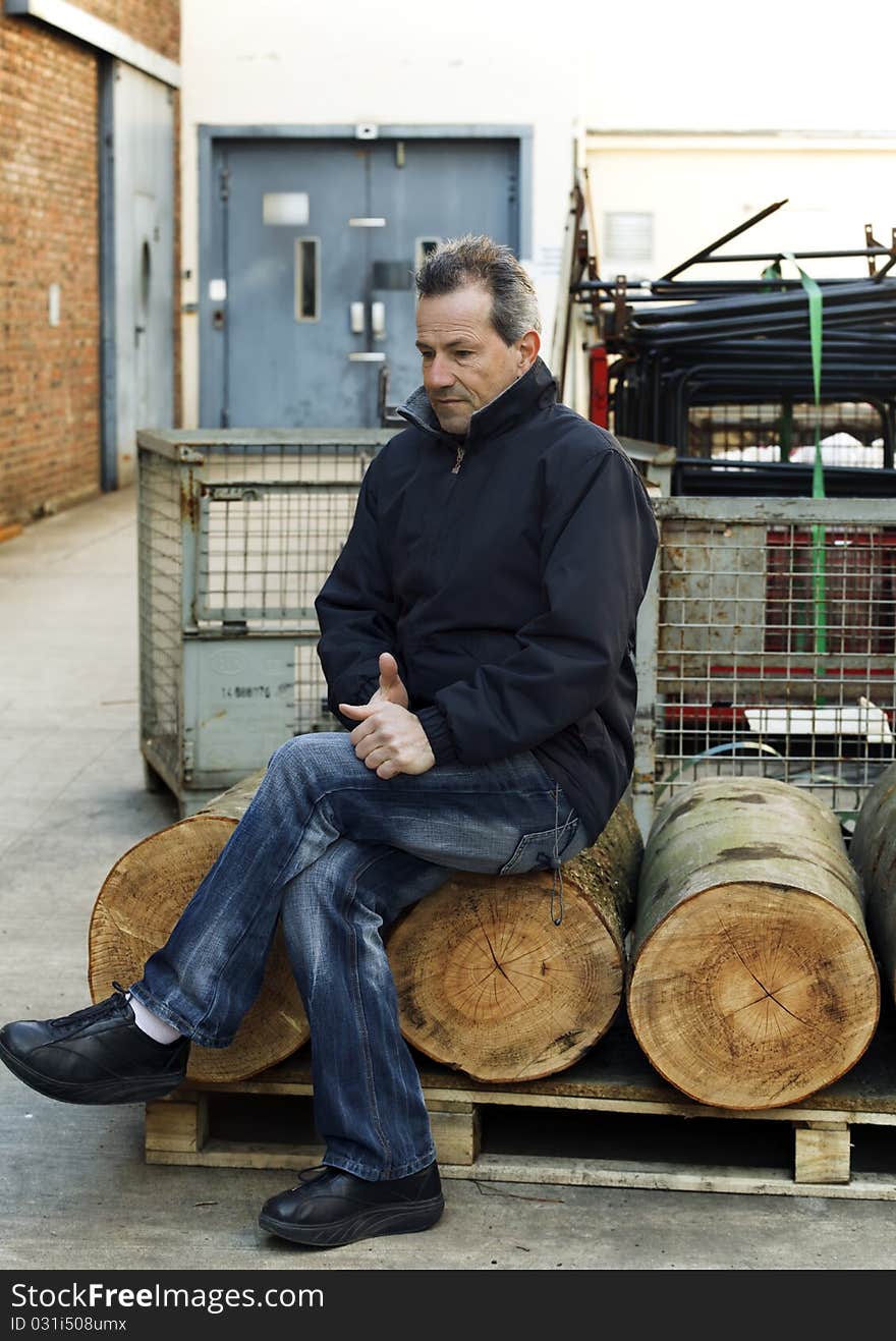 Businessman sitting next to his red bank company outdoors looking depressed. Businessman sitting next to his red bank company outdoors looking depressed.