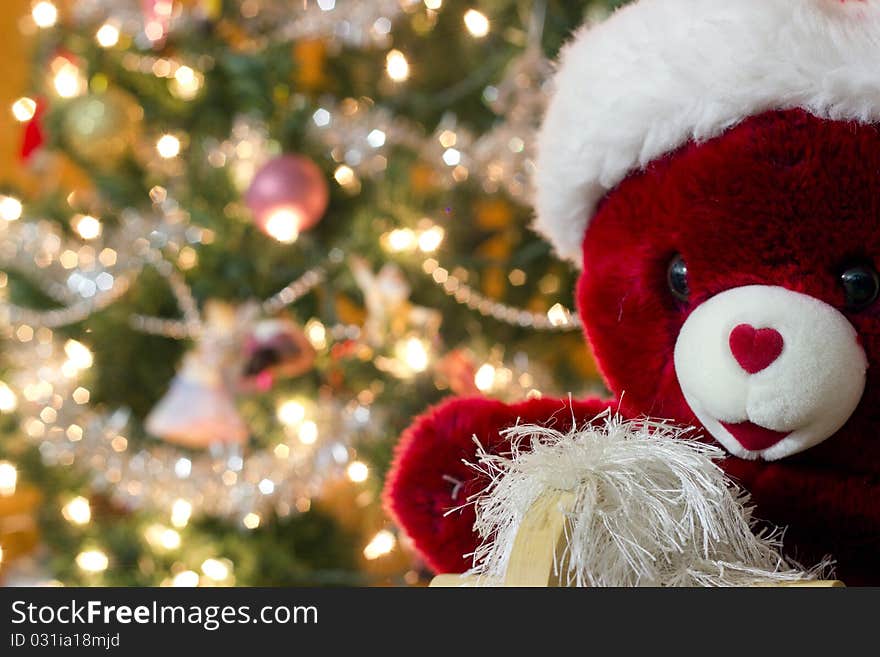 A stuffed bear sits in front of a Christmas tree. A stuffed bear sits in front of a Christmas tree.