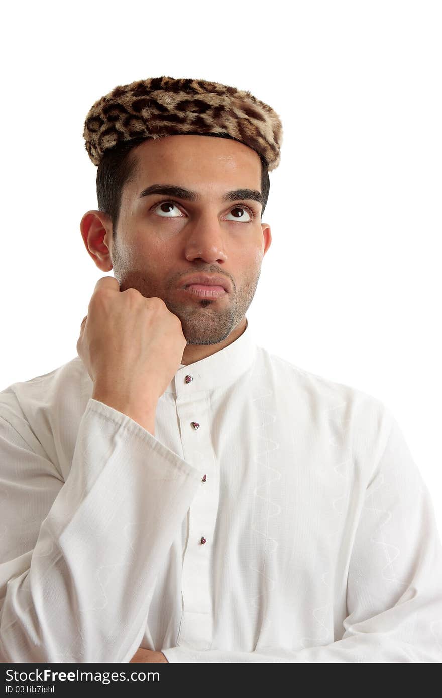 An ethnic man wering a white embroidered robe fastened with claw set rubies and wearing vintage leopard skin hat. He is looking up and thinking or pondering. Space for copy. White background. An ethnic man wering a white embroidered robe fastened with claw set rubies and wearing vintage leopard skin hat. He is looking up and thinking or pondering. Space for copy. White background.