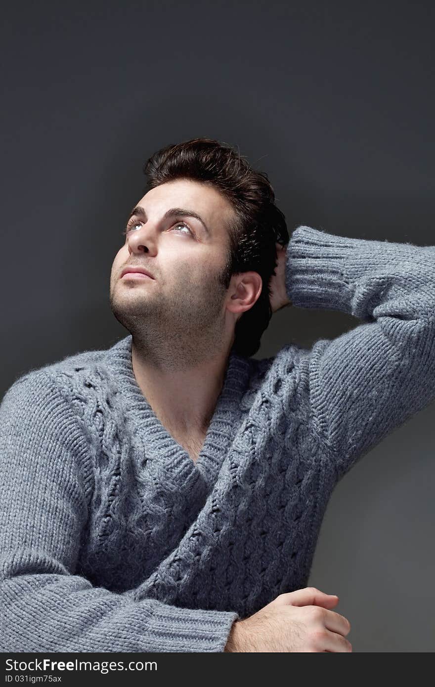 Portrait of a man in a sweater looking up - isolated on gray