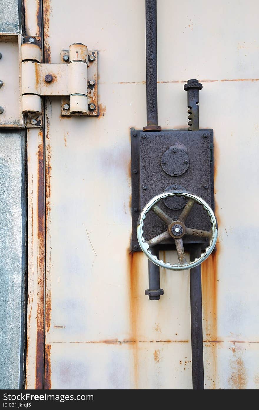 Rusty iron lock on the harbor warehouse door; focus on the wheel and lock's body. Rusty iron lock on the harbor warehouse door; focus on the wheel and lock's body