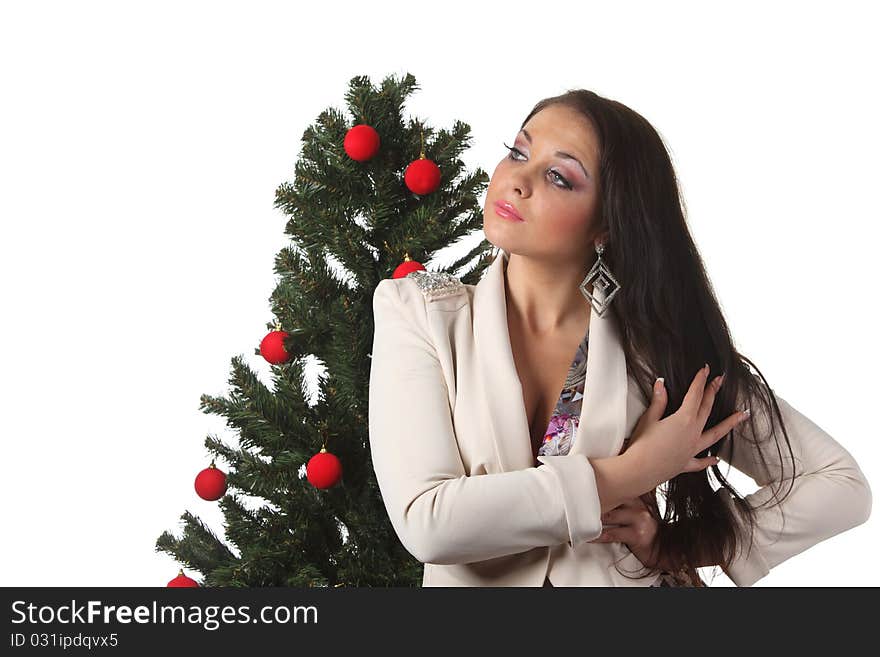 Young attractive brunette woman in a white jacket stay near a Christmas tree. Young attractive brunette woman in a white jacket stay near a Christmas tree