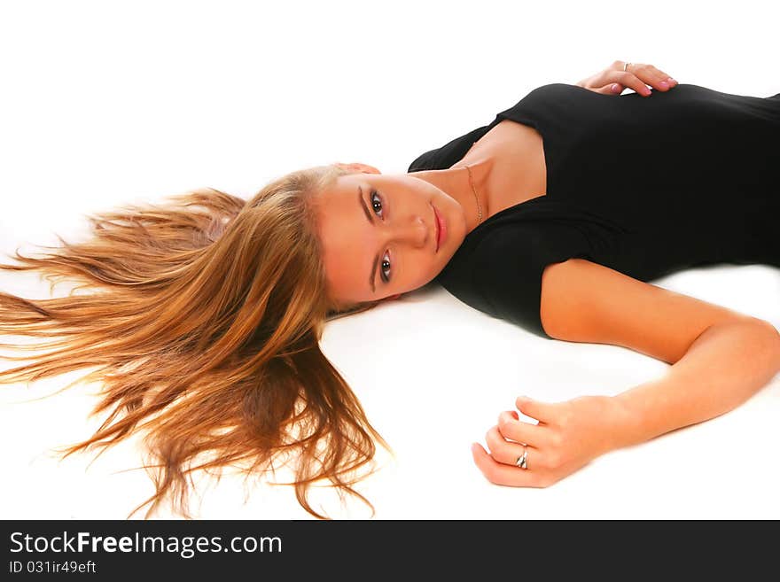 The blonde in a black dress lays on a white background and looks in the camera