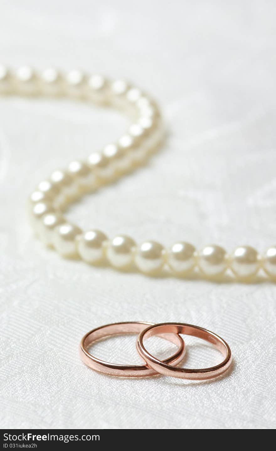 Wedding rings and pearl necklace on lace background